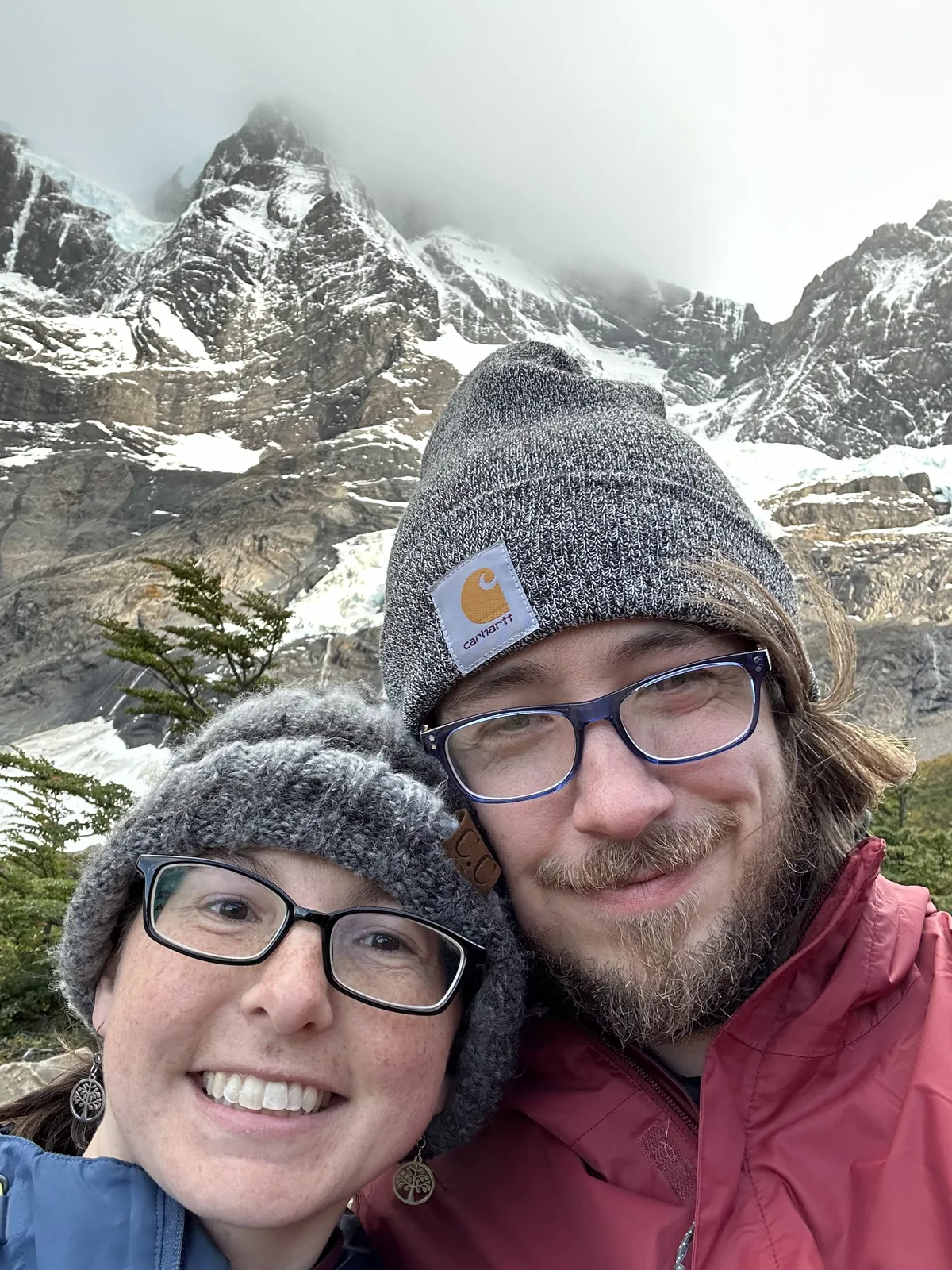 Close-up selfie in knit hats near a waterfall