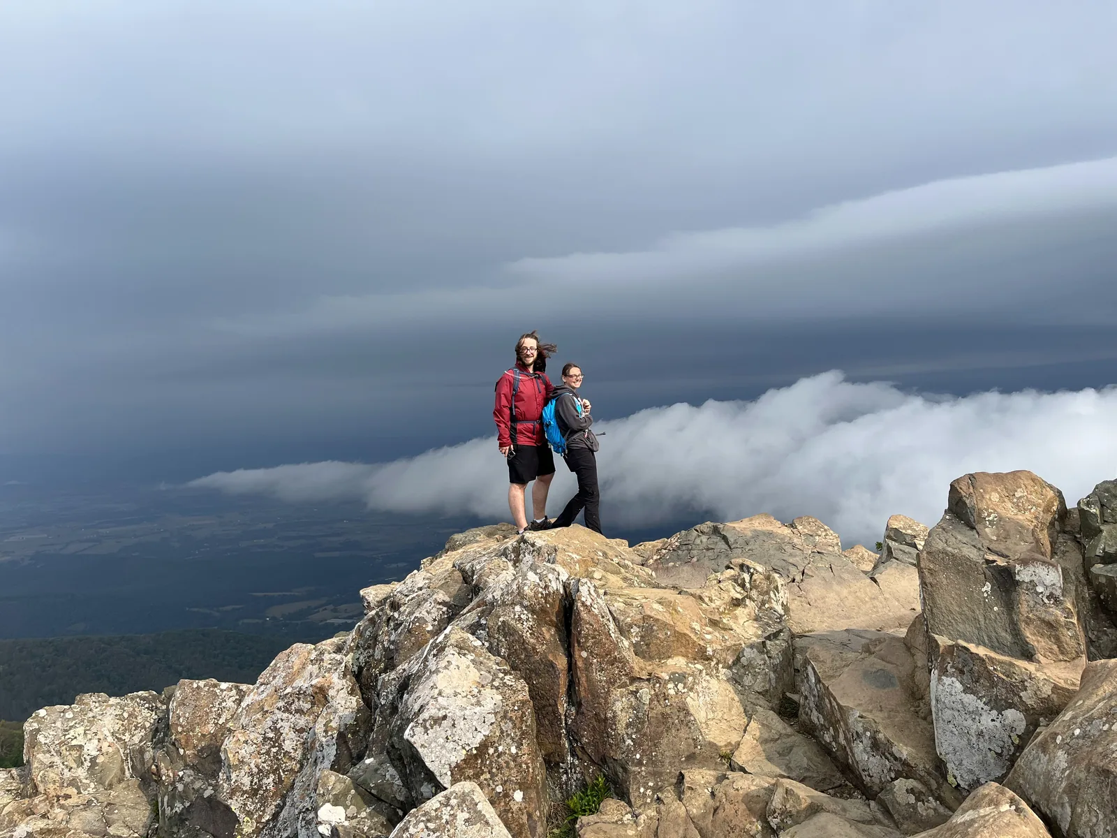 Hiker standing on a rocky peak above the clouds