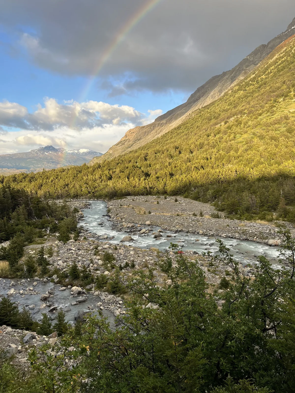 Sunlit meadow with tents below jagged peaks