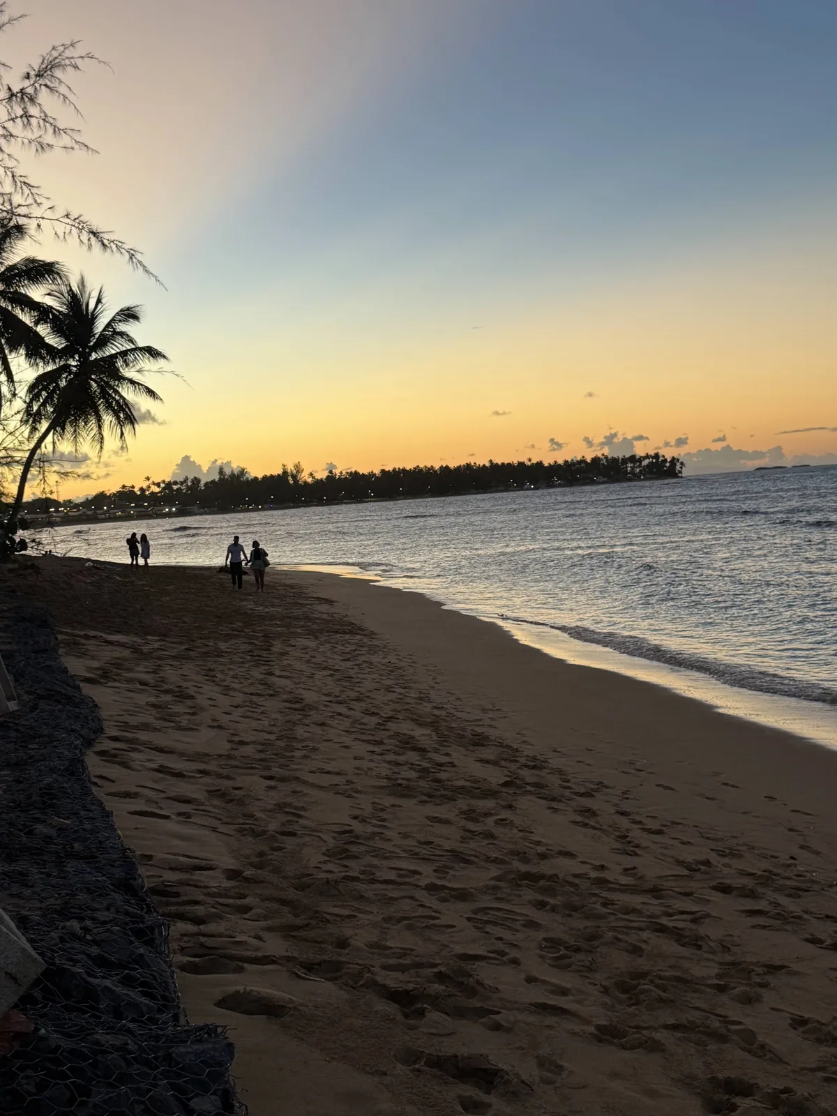 Tropical beach at sunset with silhouettes in the distance