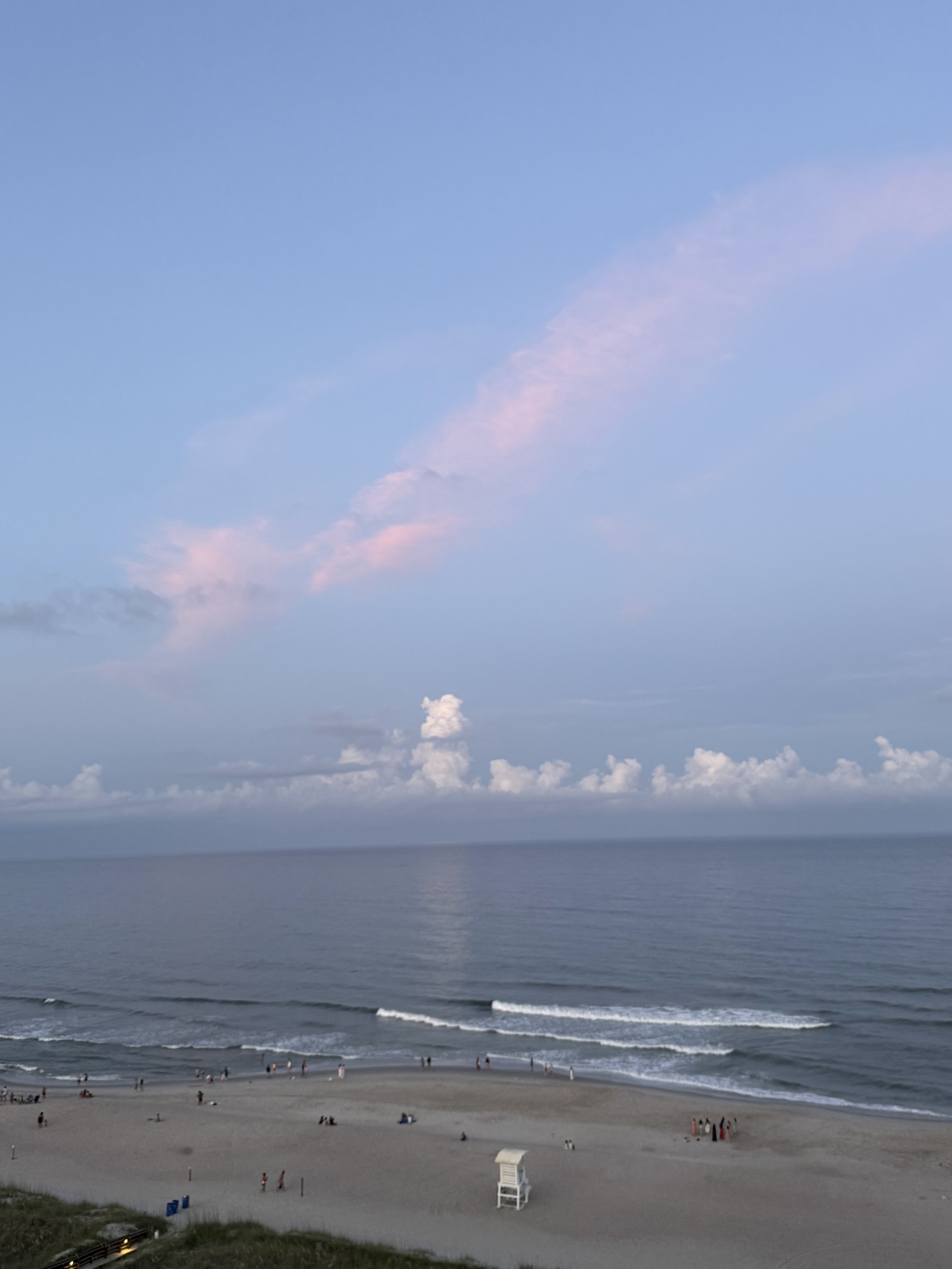 A wide view of the Carolina coast at dusk, with soft surf and a long stretch of open beach.