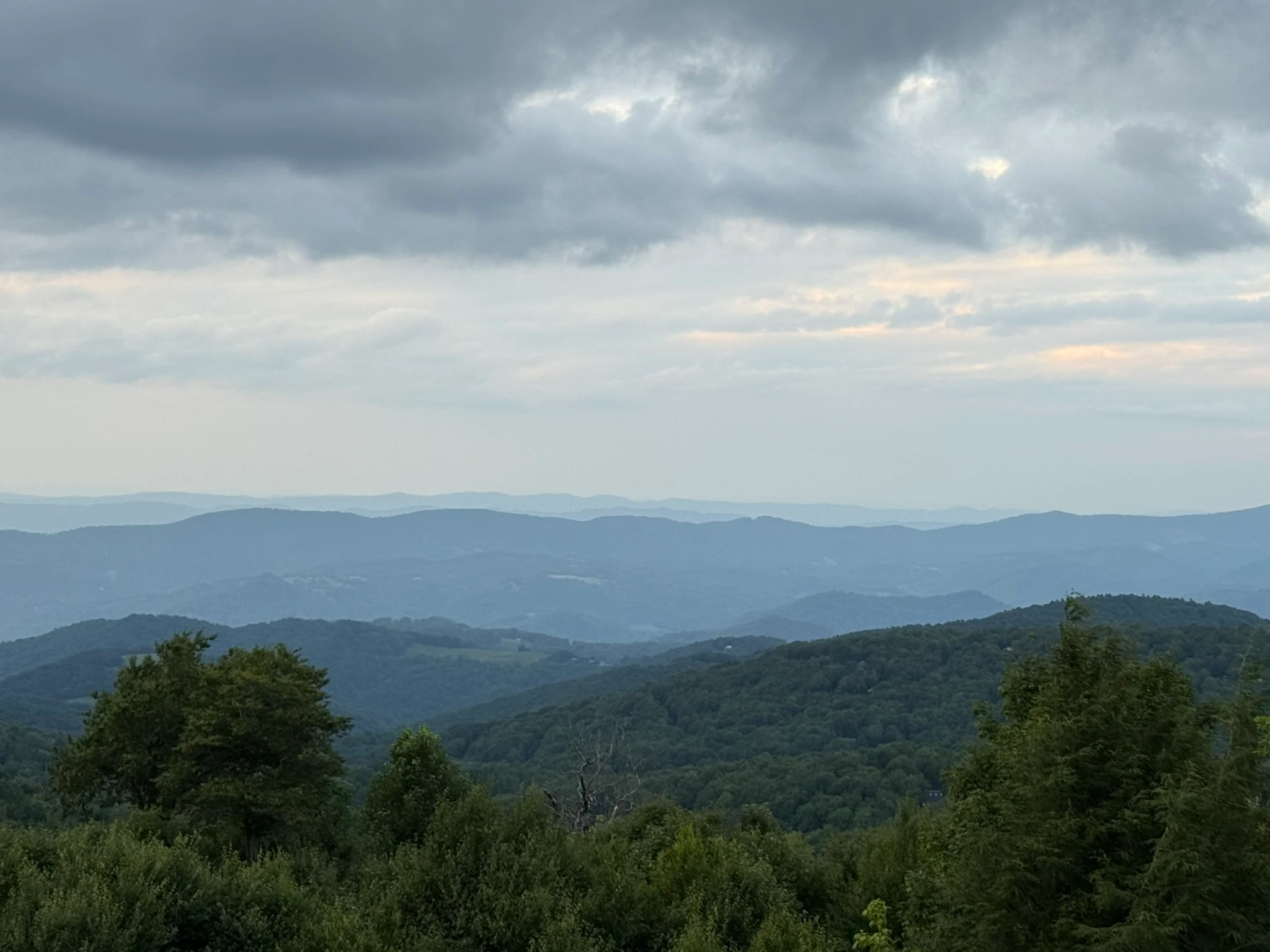 Layered Blue Ridge peaks viewed from high on Beech Mountain under a cloudy sky.