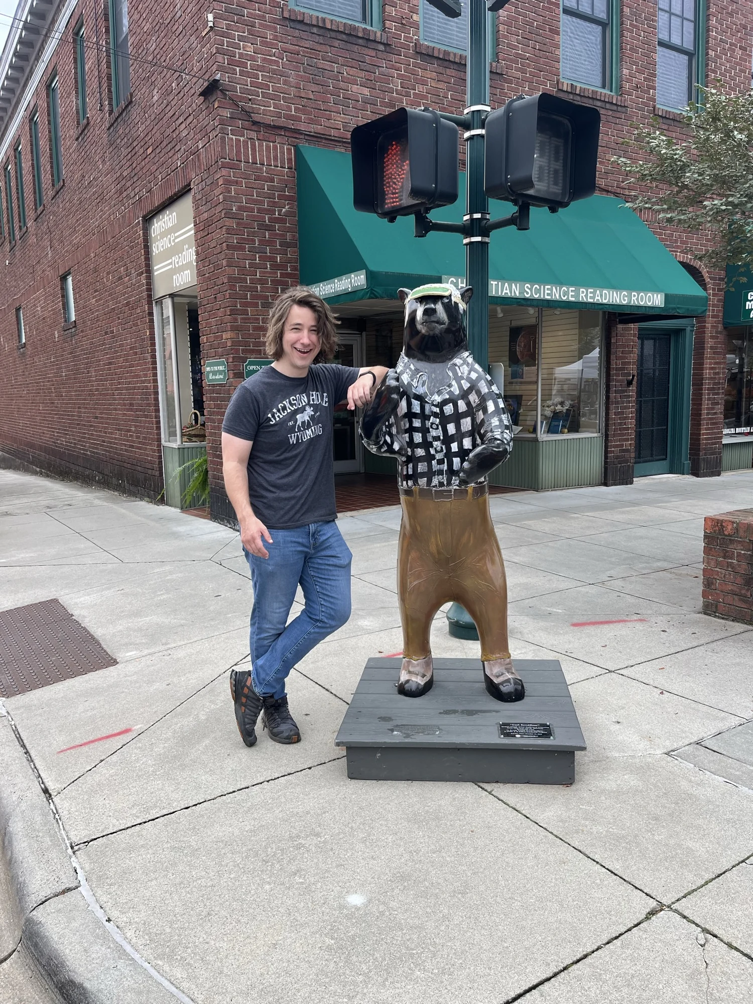 Daniel posing beside a dressed bear statue in downtown Hendersonville.