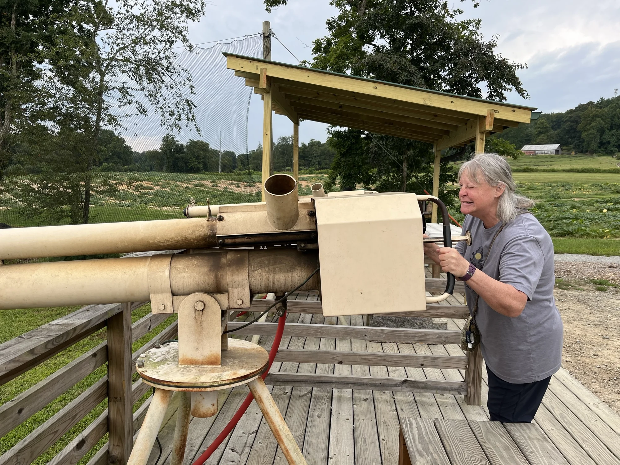 Sydney’s mom smiling as she operates a tan apple cannon at Stepp’s Hillcrest Orchard.