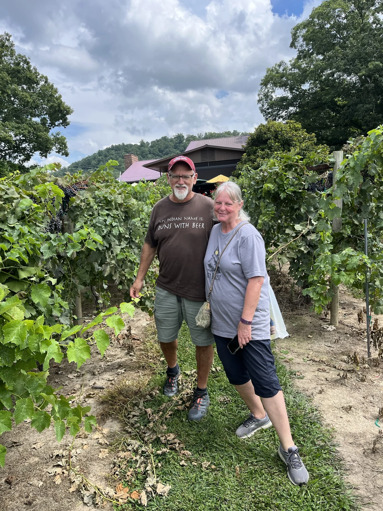 Sydney’s parents standing together among the grapevines.