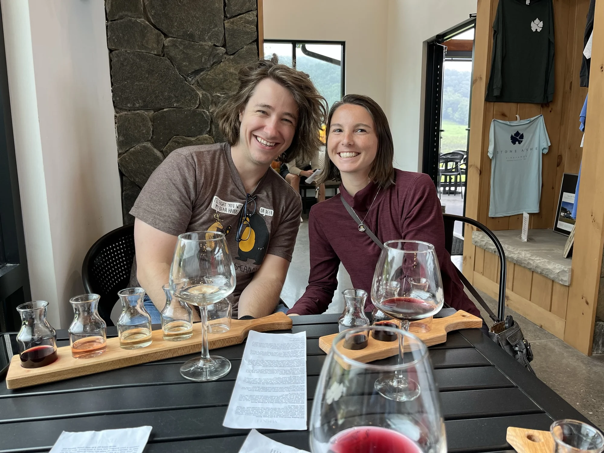 Daniel and Sydney seated together at a table with their wine tastings in Hendersonville.