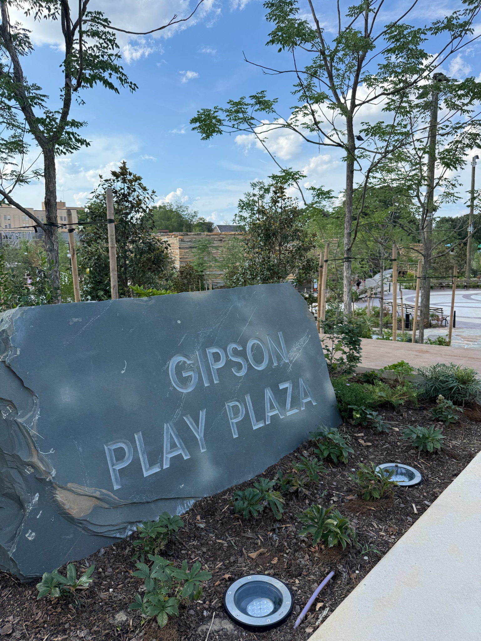 Gipson Play Plaza sign and landscaped play area at Dorothea Dix Park in Raleigh.