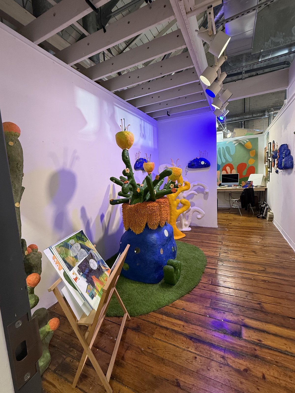 A bright gallery room at Artspace in Raleigh with sculptural work, wood floors, and colorful displays.