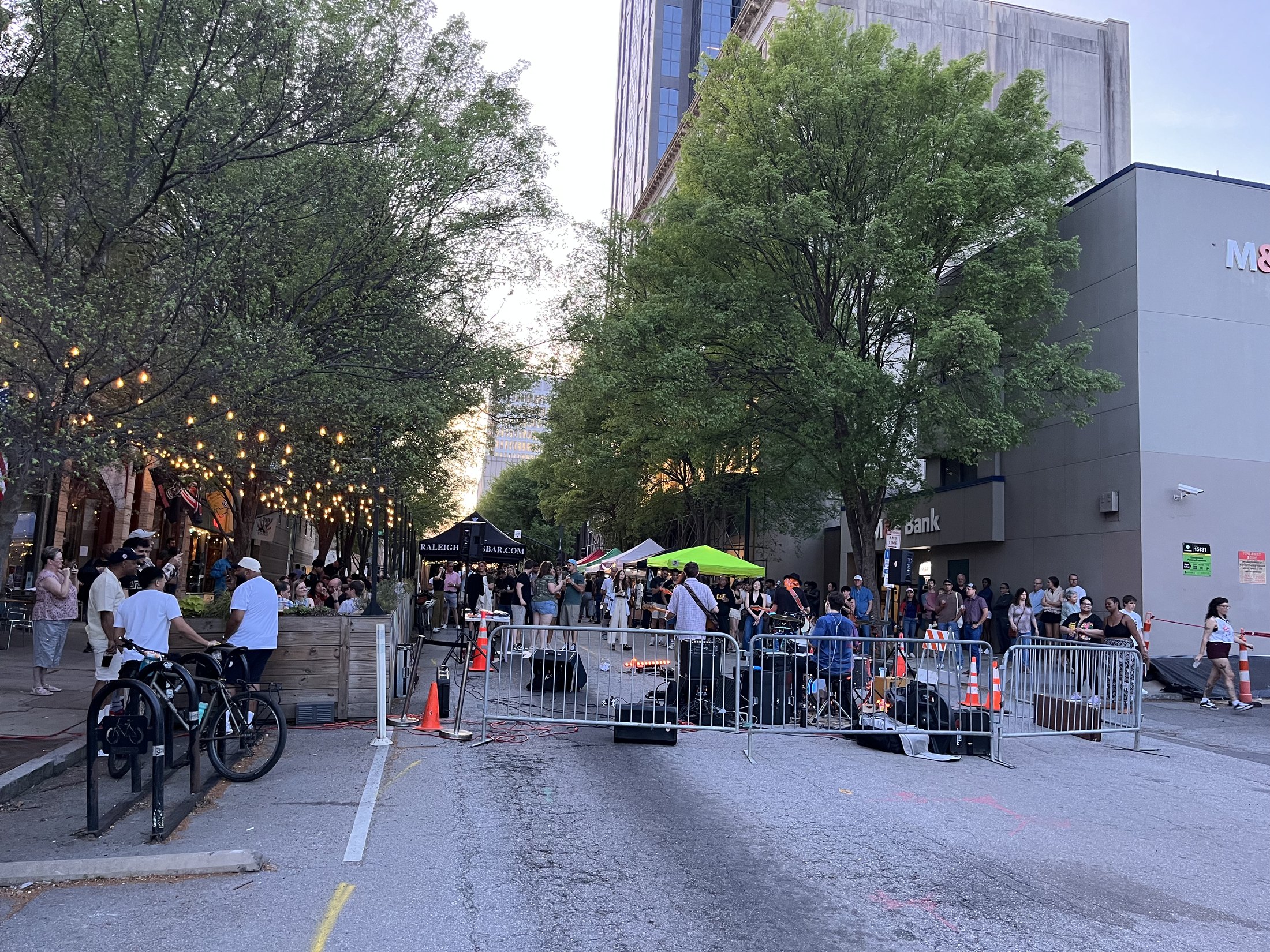 Downtown Raleigh on First Friday with people gathered beneath string lights outside the museum district.