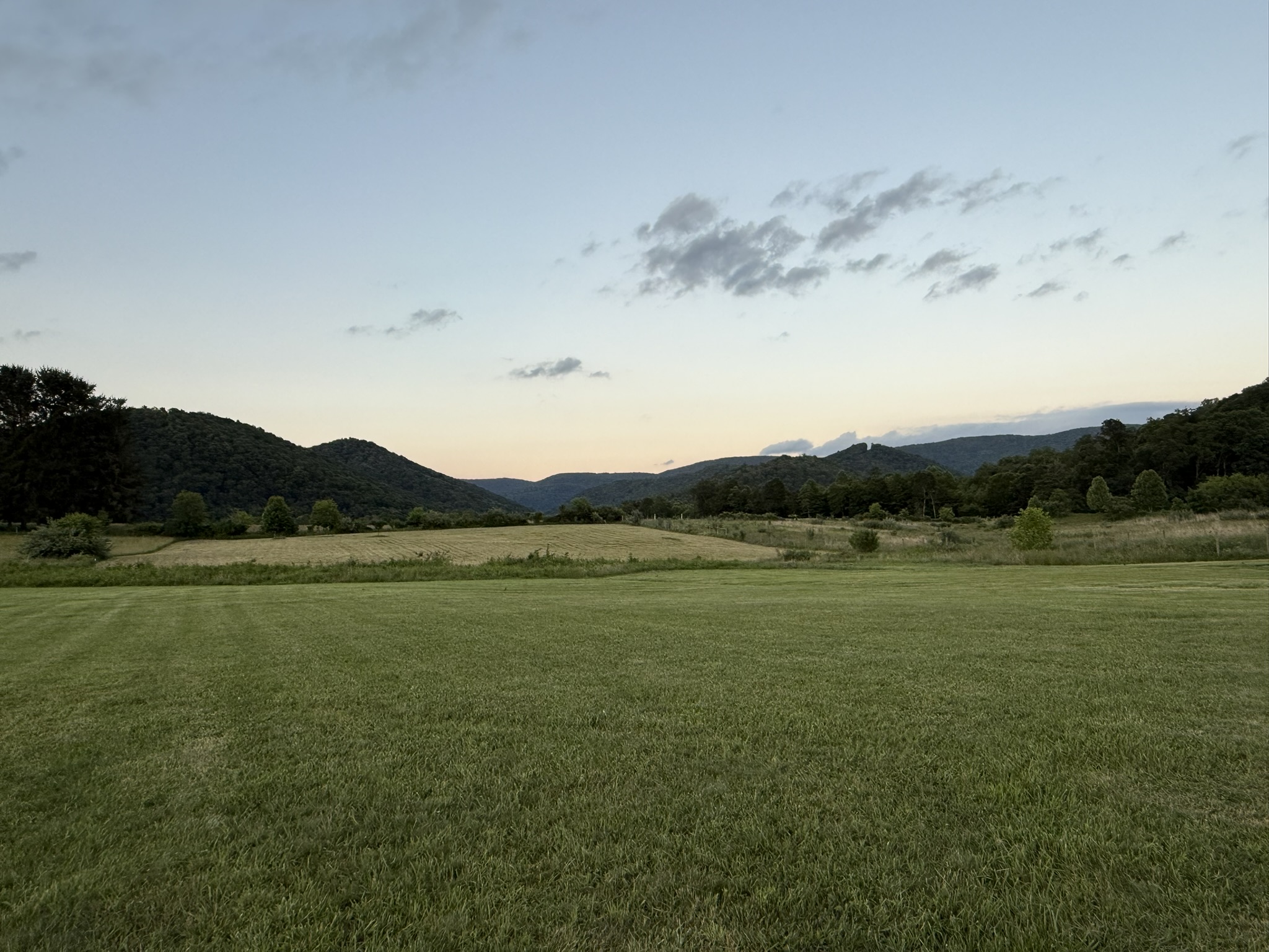 A broad West Virginia mountain valley beneath a pale evening sky.