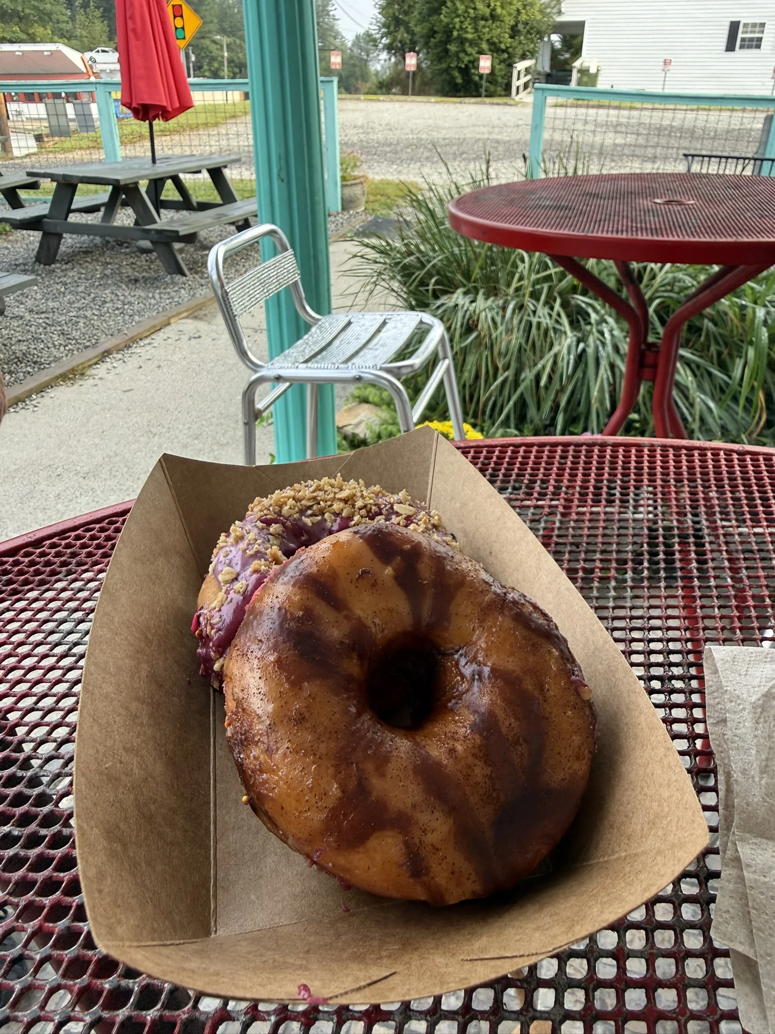 A berry-glazed ring donut in a paper tray on a red outdoor table at Hendough.