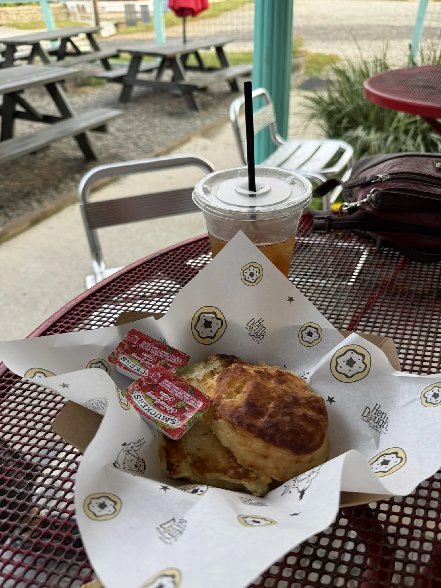 A biscuit and takeaway coffee on a red patio table outside Hendough.