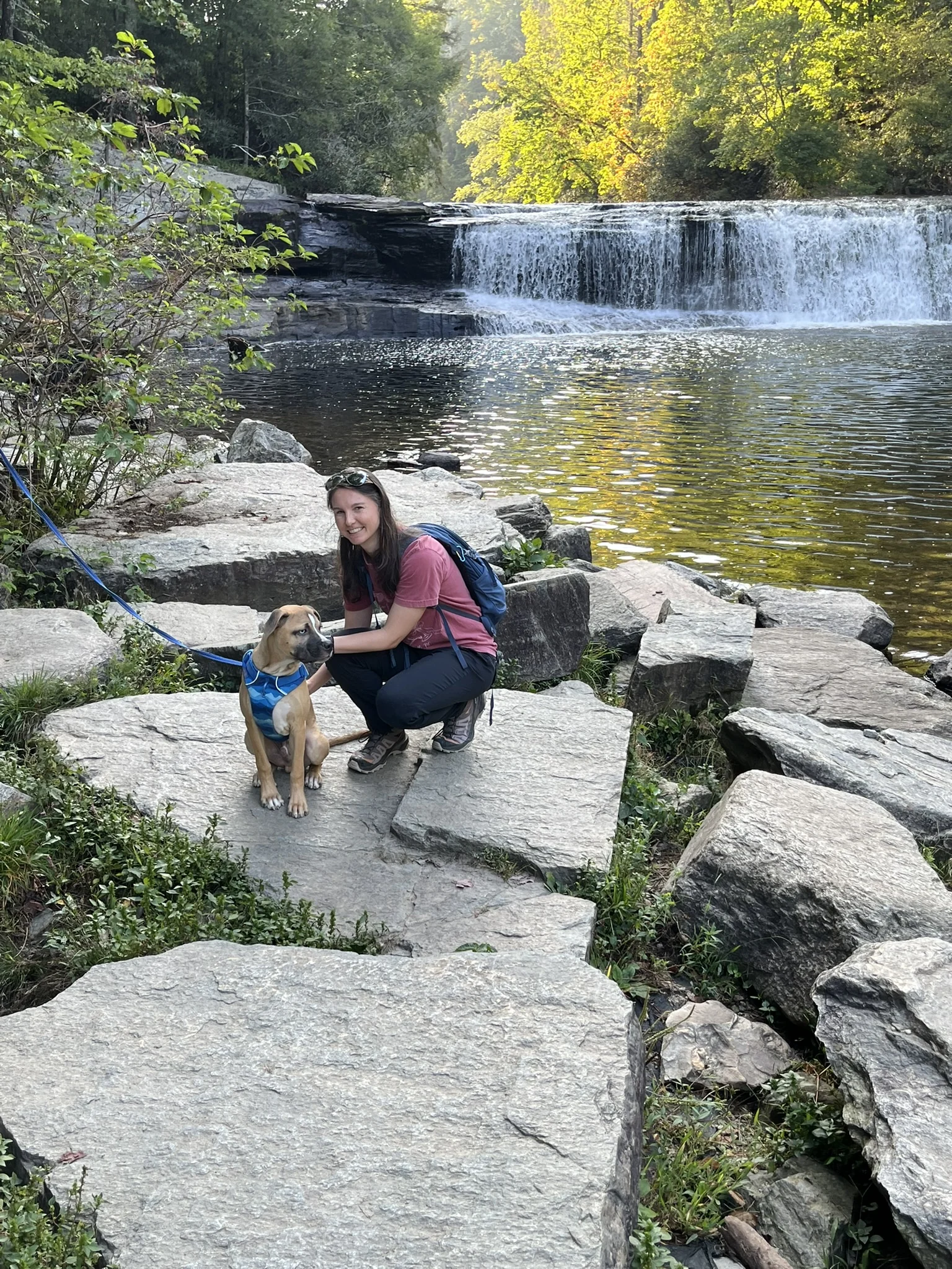 Sydney crouching beside Viktor on rocks in front of Hooker Falls.