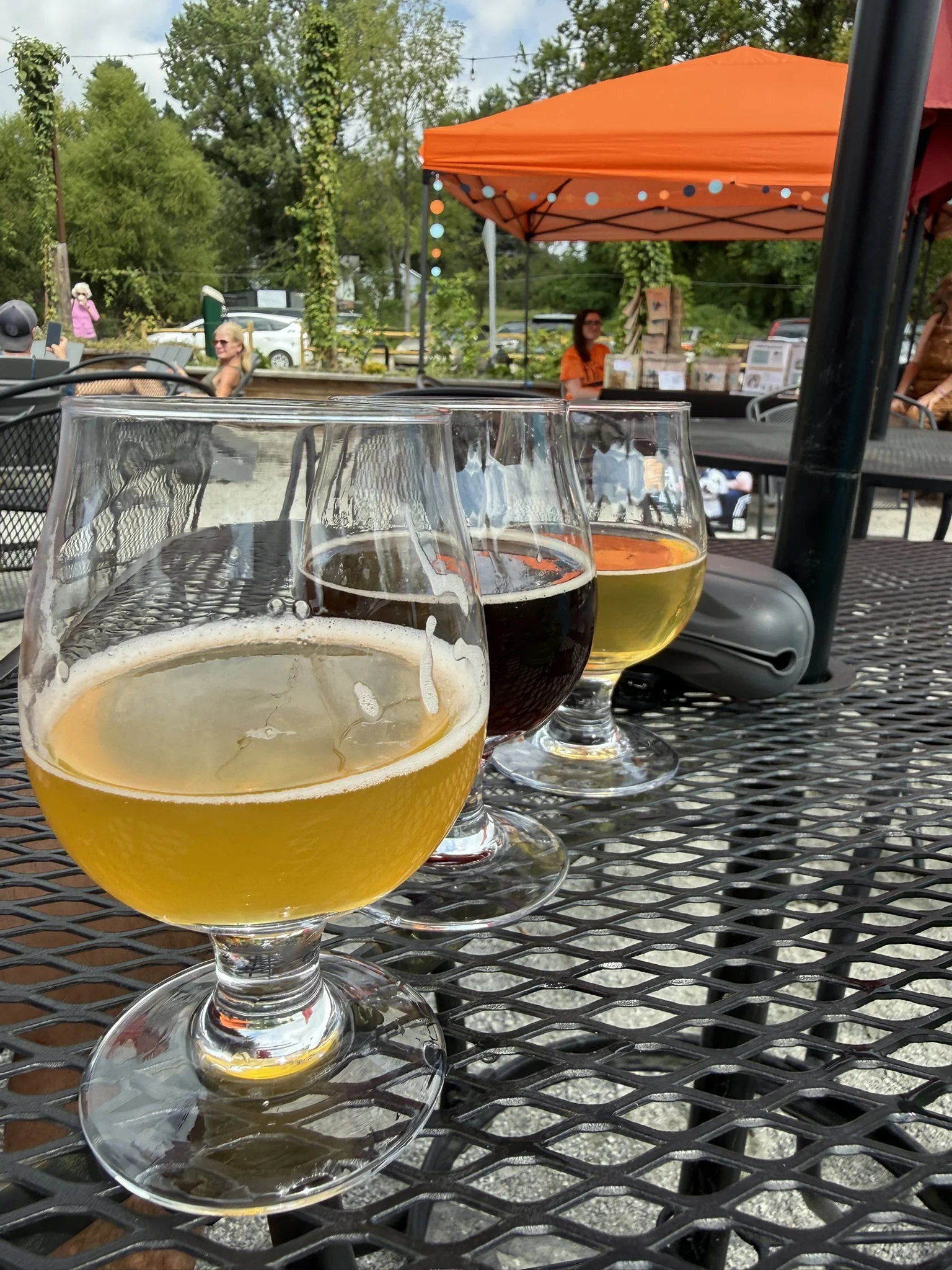 Three glasses of pale, brown and golden beer on an outdoor table at Trailside.
