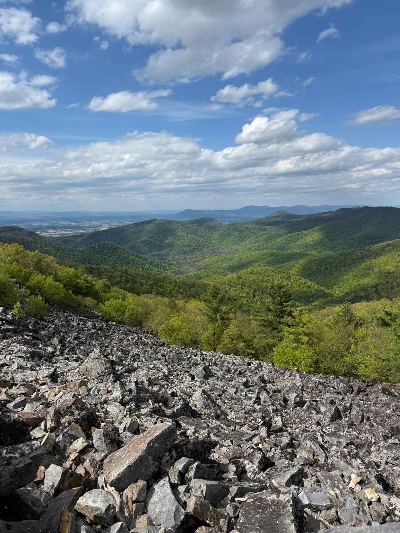 A Blackrock Summit view over green Shenandoah ridges and a rocky boulder field.