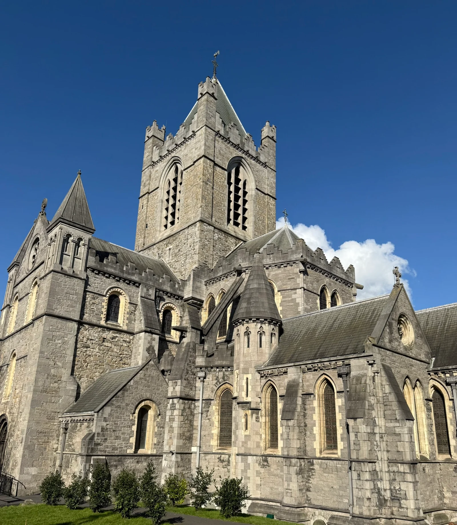Stone towers and rooflines of St. Patrick's Cathedral in Dublin under a deep blue sky.